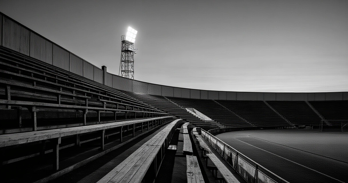 Vanha eurooppalainen jalkapallostadion iltahämärässä, kuvaa Huuhkajien historian pitkää taivalta